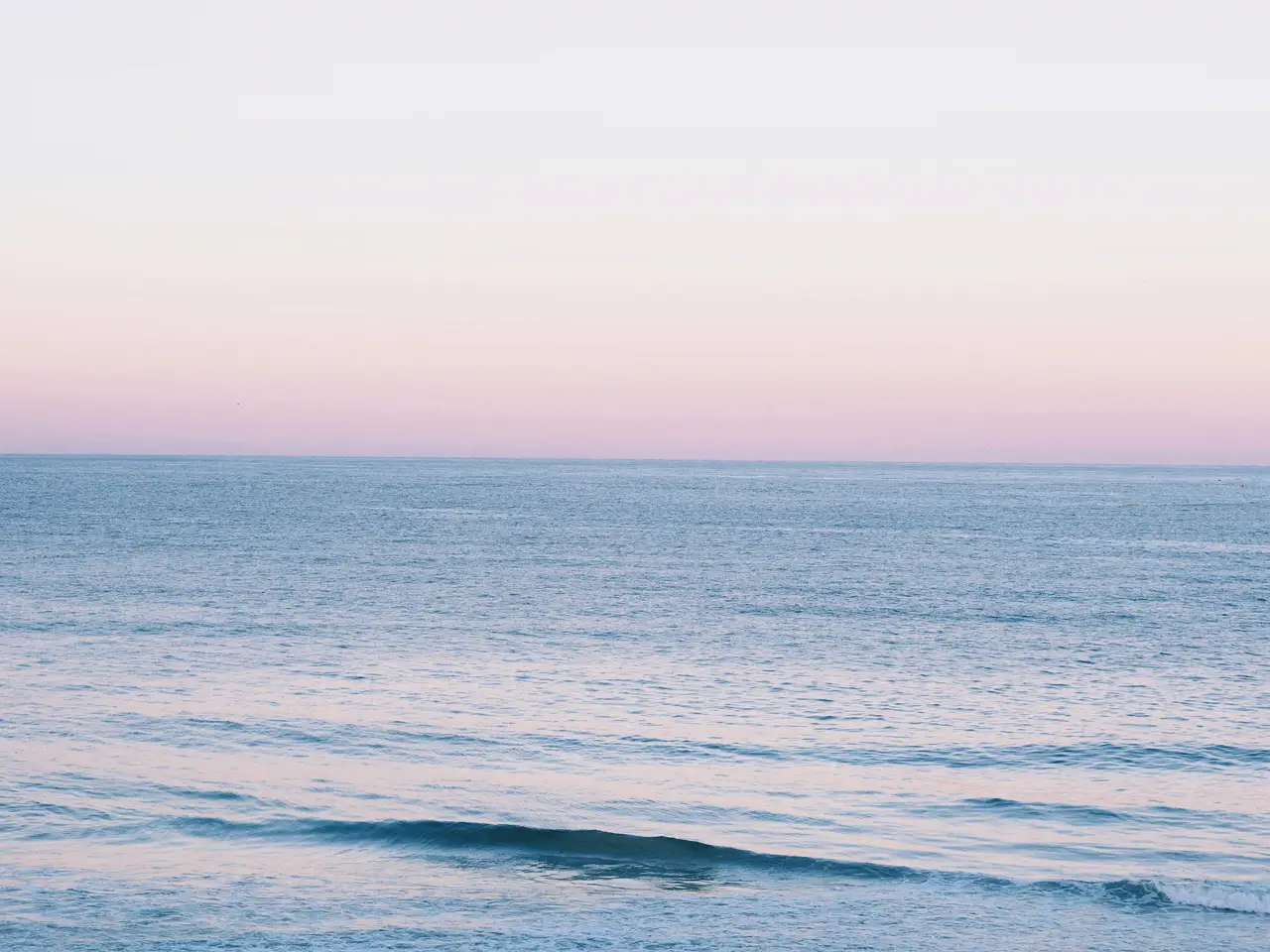 Calm sea under a soft pink sky